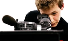 A teenage boy with a film camera in a studio