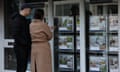 People look at properties displayed in the window of a real estate agent's office in London.