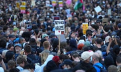 People in a crowd hold placards reading 'Refugees welcome' and other anti-racist messages.