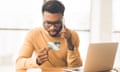 A man talking on his phone while holding a holding credit card