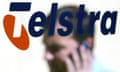 File photo of a man talking on his mobile phone as he passes a Telstra sign