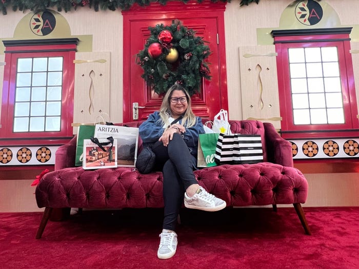 Jenny Powers is sitting on a Santa couch in the middle of the mall with six shopping bags.