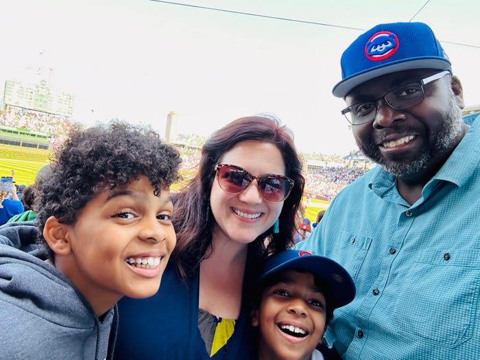 A man smiling for a photo with his wife and two children.