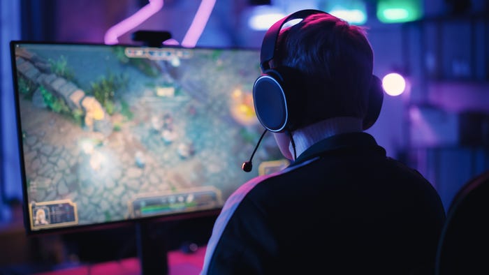 A boy wearing headphones is playing video games on a computer screen.