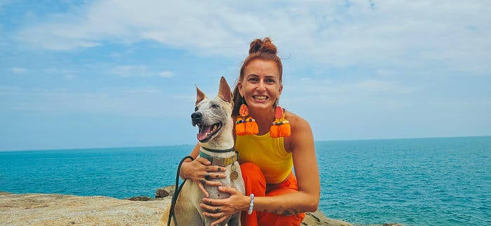 Monique Lindner and a dog smiling by the water.