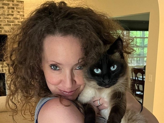 Christina Wyman smiling at the camera and holding one of her cats.