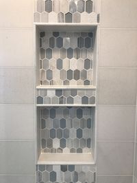 This accent tile is truly stunning thanks to the beautiful combination of light blue textured glass, brushed metal, and white and grey stone tiles. Surrounded by the equally beautiful San Dano marble wall tile, we sent the picket tile vertically through the double niches.