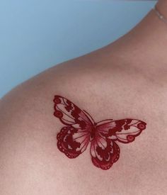 a red butterfly tattoo on the back of a woman's shoulder and chest area