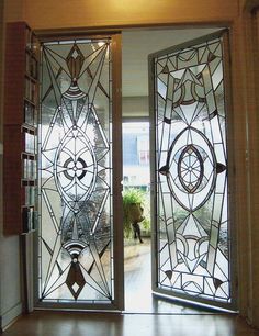 an open glass door with decorative designs on the front and side panels, leading into a hallway