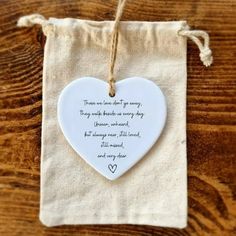 a white heart shaped ornament hanging from a string on top of a wooden table