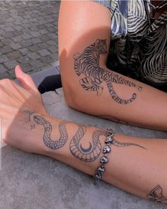 two people sitting on the ground with tattoos on their arms