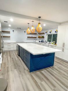 a large kitchen with white cabinets and blue island