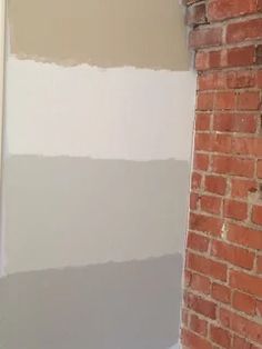 a brick wall is painted with gray and white paint in the corner of a room