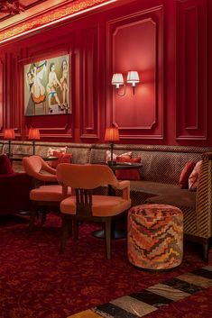 a room filled with lots of red walls and furniture next to lamps on either side of the wall