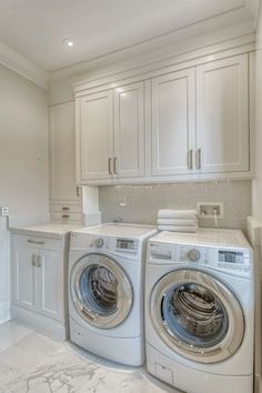 a washer and dryer in a white laundry room with marble counter tops on the floor