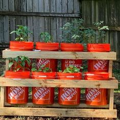 several red buckets stacked on top of each other in front of a wooden fence