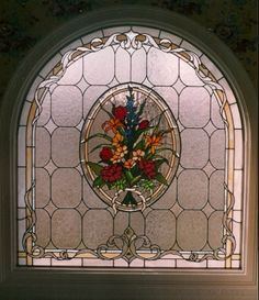 a stained glass window with flowers in the center and an ornate frame around it,