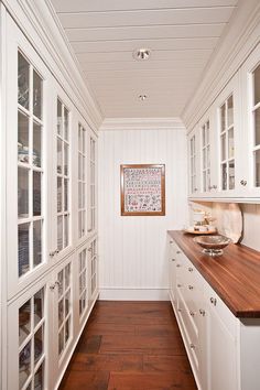 a kitchen with white cabinets and wood counter tops