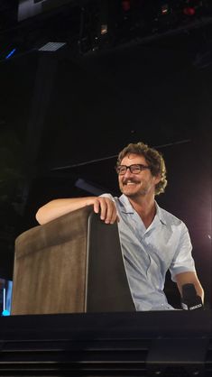 a man sitting at a podium with his hand on the back of it's head