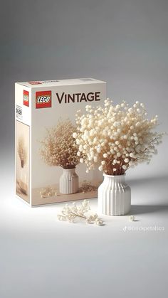 a white vase filled with baby's breath flowers next to a box of legos