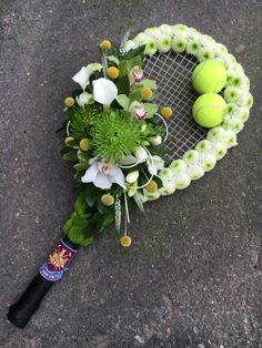 a tennis racquet laying on the ground with flowers and balls in front of it