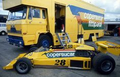 a yellow race car sitting in front of a truck