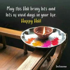 a small metal plate with a lit candle on it and the words happy holi written in