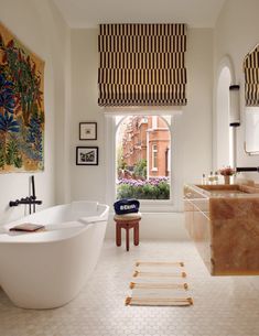 a bath room with a large tub next to a window and a painting on the wall