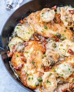 a skillet filled with chicken, artichokes and sauce