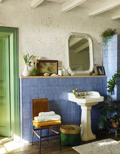 a bathroom with blue tile and green door, sink, mirror and plant in the corner