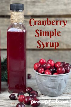 cranberry simple syrup in a glass bottle next to fresh cranberries on a wooden table