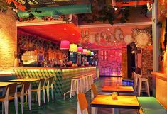 the interior of a brightly lit restaurant with wooden tables and colorful lights on the ceiling