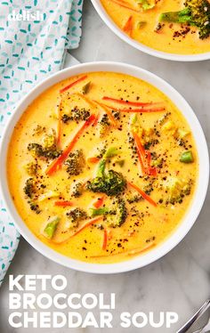 two bowls of broccoli cheddar soup on a marble table with spoons