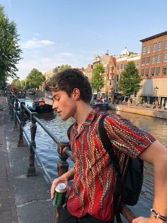 a young man standing on the side of a river