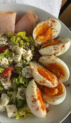 a white plate topped with hard boiled eggs and salad