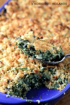 a blue dish filled with broccoli casserole on top of a wooden table