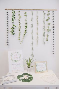 a white table topped with lots of greenery and greeting cards next to a plant