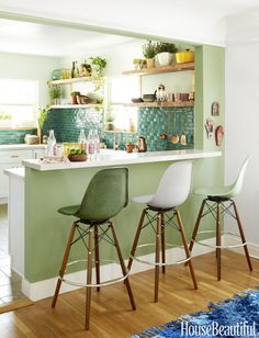 two stools in front of a kitchen bar with green tile backsplash and white cabinets