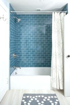 a blue tiled bathroom with white fixtures and shower curtain in the bathtub, next to an open door