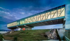 a bridge that is on top of a hill with grass and rocks below it at night