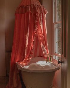 an old bathtub with curtains hanging over it