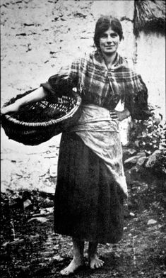 an old black and white photo of a woman holding a basket