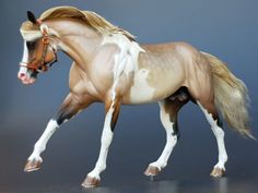 a brown and white horse is running on a gray surface with its head turned to the side