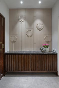 an entry way with two vases on the counter and three wall lights above it