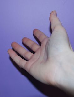 a person's hand reaching for something on a purple surface