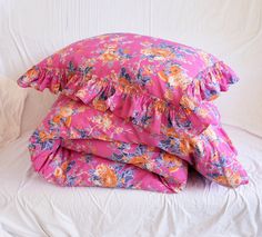 two pillows stacked on top of each other in front of a white background with pink and orange flowers