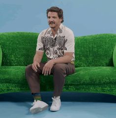 a man sitting on top of a green couch in front of a blue and green wall