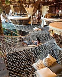 a woman laying on top of a hammock in a room filled with beds