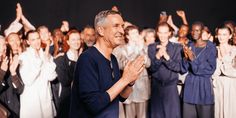 a man standing in front of a group of people with his hands up to the sky