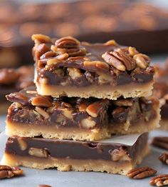 three pieces of pecan bar stacked on top of each other with chocolate and pecans